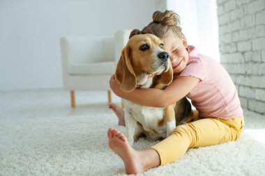 Köpekli bir çocuk. Küçük kız evde bir köpekle oynuyor. Çocuk ve hayvan.