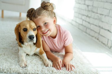 Köpekli bir çocuk. Küçük kız evde bir köpekle oynuyor. Çocuk ve hayvan.