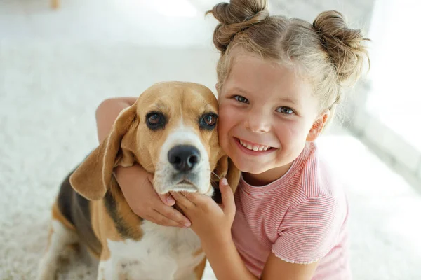 Köpekli bir çocuk. Küçük kız evde bir köpekle oynuyor. Çocuk ve hayvan.