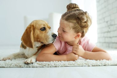 Köpekli bir çocuk. Küçük kız evde bir köpekle oynuyor. Çocuk ve hayvan.