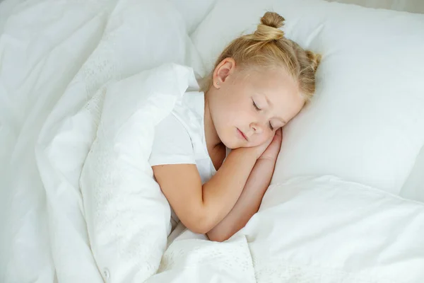 Ragazzina a letto con biancheria bianca. Un bambino a casa la mattina si sveglia nella sua stanza. — Foto Stock