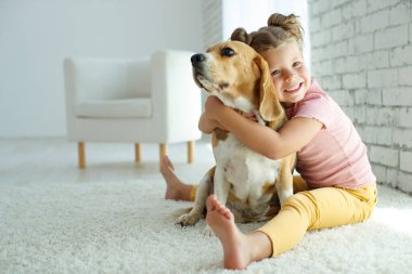 Köpekli bir çocuk. Küçük kız evde bir köpekle oynuyor. Çocuk ve hayvan.