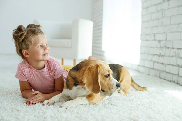 Un niño con un perro. La niña juega con un perro en casa. Niño y animal. — Foto de Stock