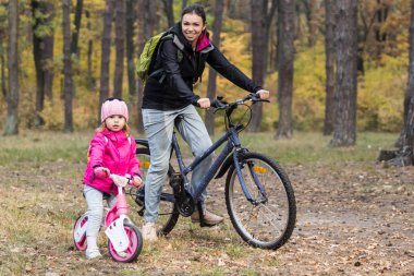 Mutlu anne ve kızı sonbahar park bisiklet sürme.