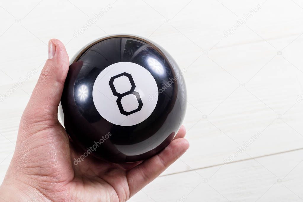 Magic prediction eight ball in hand, on the white background.