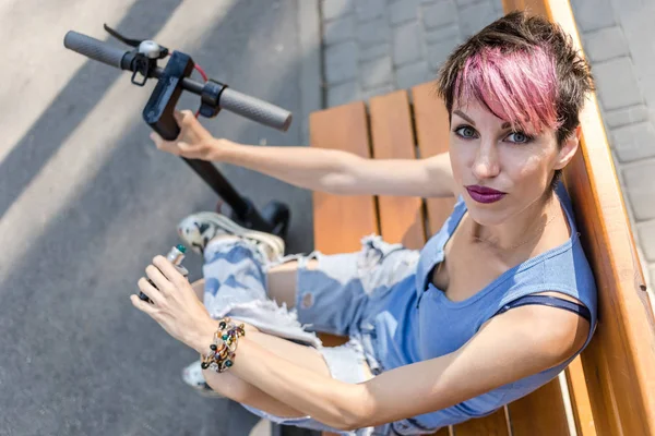 Fresco donna attraente con i capelli rosa, gode di cavalcare un elettrico — Foto Stock