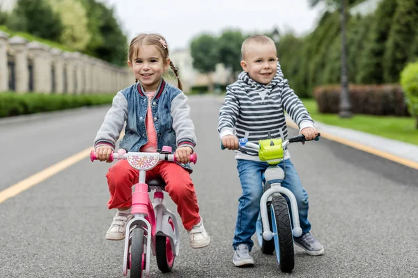 Šťastné děti s koly, které se na cestách baví v denním provozu. — Stock fotografie