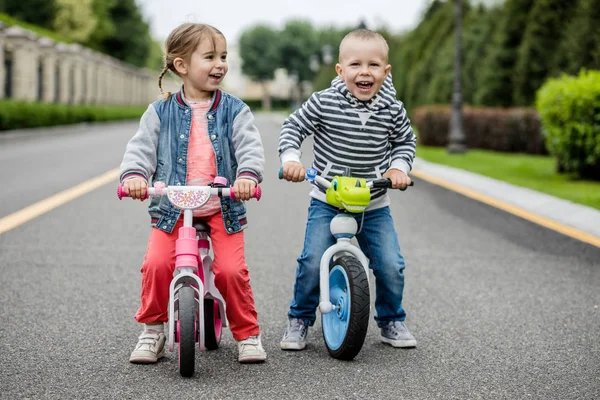 Happy Kids med cyklar ha kul på vägen på dagen tid. — Stockfoto