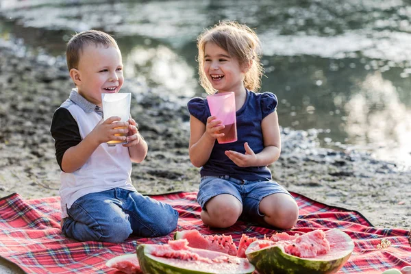 Happy kids with apple juice having fun on the beach. — Stock Photo, Image