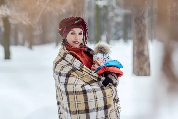 Mamma bär hennes Baby flicka bär röd jacka och sling. — Stockfoto