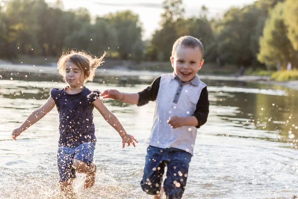 Duas crianças felizes correndo pela água no verão — Fotografia de Stock