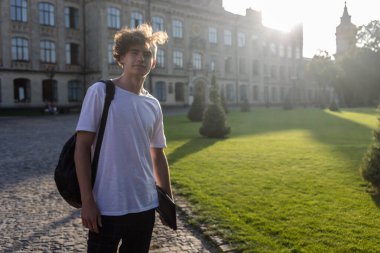 Öğrenci kampüsünde ana binanın önünde öğreniyor.