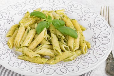 Penne rigate makarna fesleğen pesto ile plaka closeup.