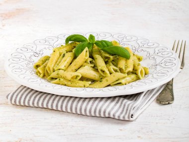 Tabak makarna türü penne rigate beyaz arka plan üzerinde fesleğen pesto ile.