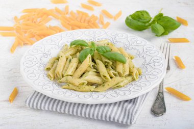 Penne rigate makarna beyaz arka plan üzerinde fesleğen pesto ile.
