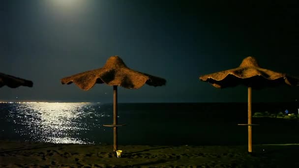 Playa Por Noche Verano Con Sombrillas Paja Luna Reflejándose Mar — Vídeo de stock