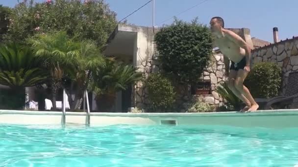 男子跳入蓝色游泳池 慢动作 侧视图 — 图库视频影像
