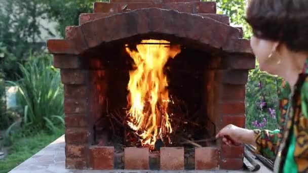 Stoking feu dans une cheminée de jardin — Video