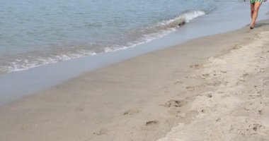 Beyaz adam tatilde mayo yla kumda yürürken ayakları deniz suyunda
