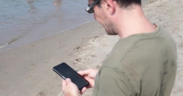 Běloch Kontrolující Zprávy Mobilu Při Procházce Pláži Turista Slunečními Brýlemi — Stock video