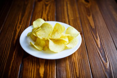 Beyaz bir tabak içinde gevrek patates cipsi