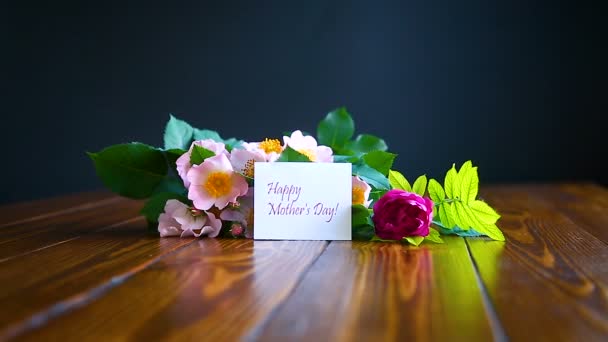 Mooie bloeiende rozen en een wenskaart voor de moeder — Stockvideo