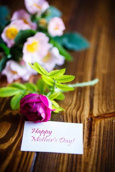 Beautiful blooming roses and a greeting card for the mother — Stock Photo, Image