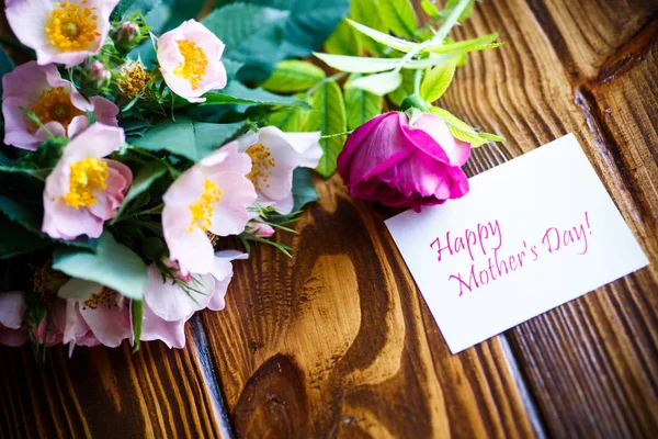 Mooie bloeiende rozen en een wenskaart voor de moeder — Stockfoto