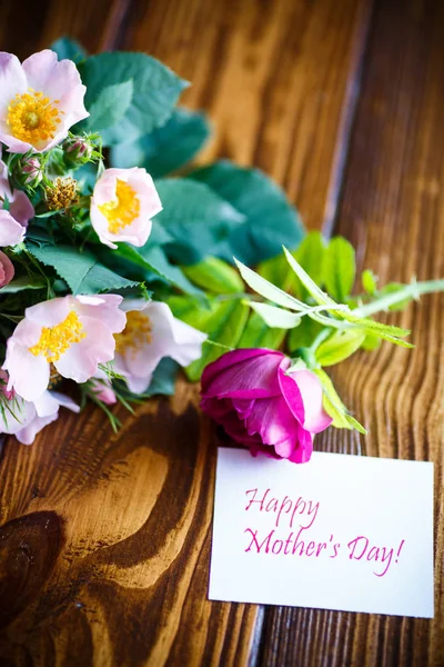 Beautiful blooming roses and a greeting card for the mother — Stock Photo, Image