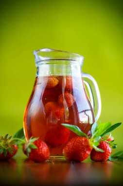 Olgun kırmızı çilek cam sürahi bir tablo içinde tatlı komposto