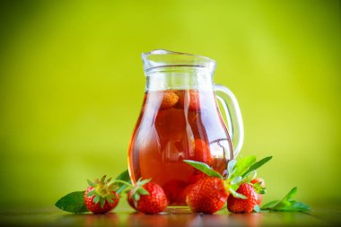 Olgun kırmızı çilek cam sürahi bir tablo içinde tatlı komposto