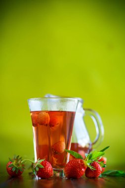 Olgun kırmızı çilek cam sürahi bir tablo içinde tatlı komposto