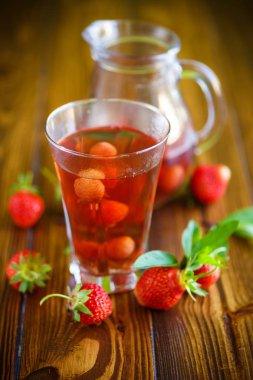 Olgun kırmızı çilek cam sürahi bir tablo içinde tatlı komposto