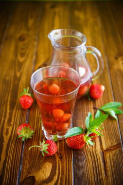 Olgun kırmızı çilek cam sürahi bir tablo içinde tatlı komposto