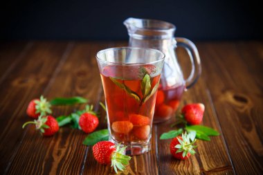 Olgun kırmızı çilek cam sürahi bir tablo içinde tatlı komposto