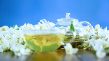 Yasemin çiçeklerle bir cam Çaydanlık bir tabloda çay