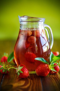 Olgun kırmızı çilek cam sürahi bir tablo içinde tatlı komposto