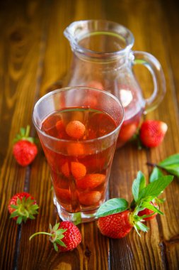 Olgun kırmızı çilek cam sürahi bir tablo içinde tatlı komposto