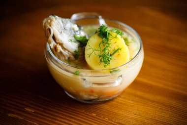 ahşap bir masa üzerinde bir cam kasede balıklı sebze çorbası