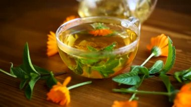 Şifalı taze sıcak çay bir fincan ahşap bir masa üzerine calendula çiçekli