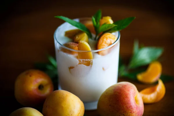 Zelfgemaakte yoghurt met rijpe abrikozen op houten tafel — Stockfoto