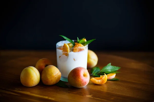 Homemade yogurt with ripe apricots on wooden table — Stock Photo, Image