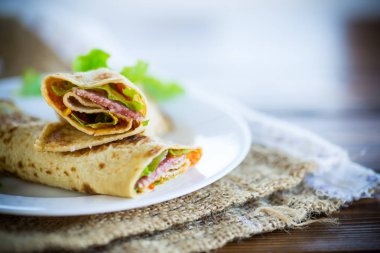 salata yaprakları ve ahşap bir masa üzerinde bir tabak içinde pastırma ile ince krep