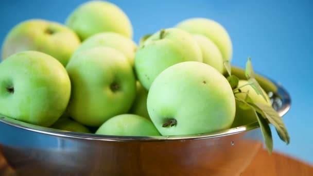 Las manzanas jugosas verdes en un bol sobre un azul — Vídeo de stock