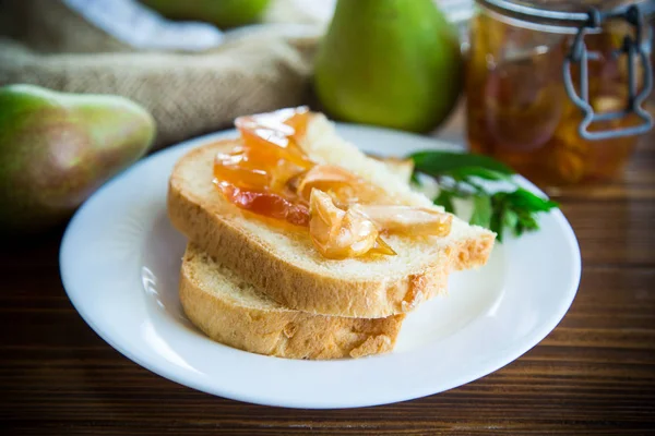 pieces of bread with sweet home-made fruit jam from pears and apples in a plate on a wooden table