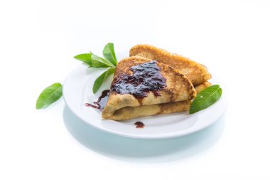 beyaz bir arka plan üzerine bir tabak içinde nane fışkın ve reçel olan bir üçgen şeklinde ince tatlı krep katlanmış