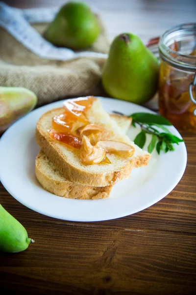 pieces of bread with sweet home-made fruit jam from pears and apples in a plate on a wooden table