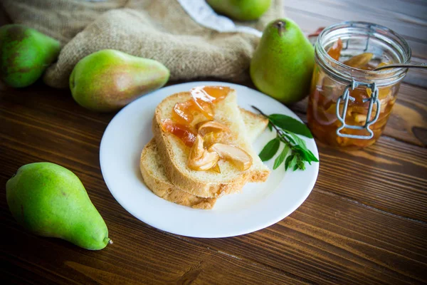 pieces of bread with sweet home-made fruit jam from pears and apples in a plate on a wooden table
