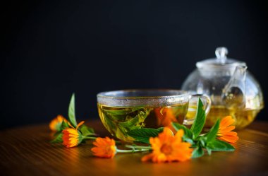 taze sıcak çay otlar ve ahşap bir masa üzerinde bir cam fincan kadife çiçeği çiçek