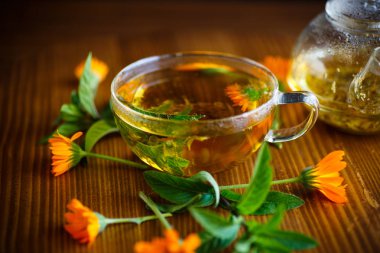 taze sıcak çay otlar ve ahşap bir masa üzerinde bir cam fincan kadife çiçeği çiçek